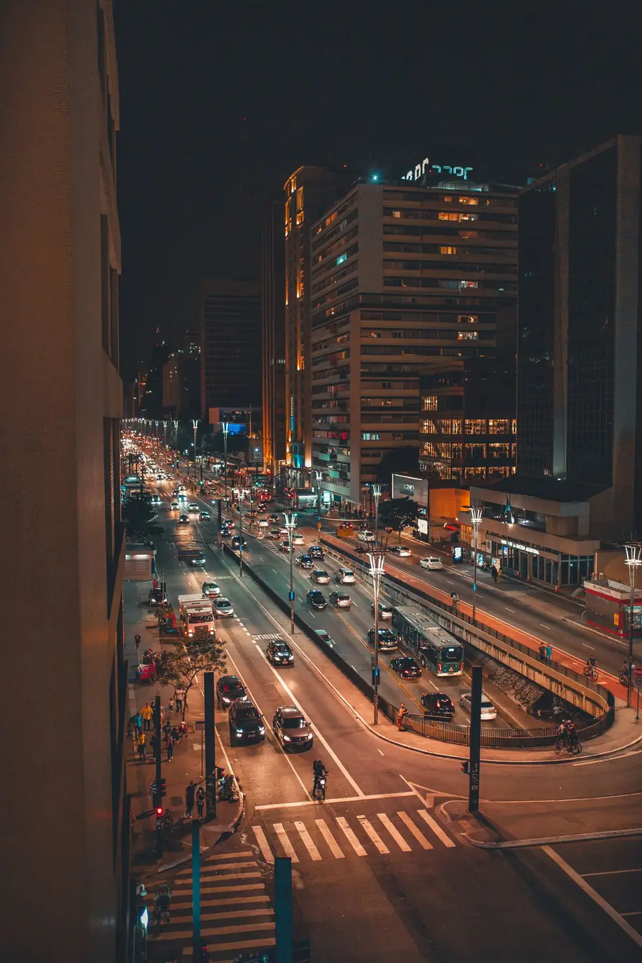 Avenida movimentada de São Paulo à noite, com trânsito intenso